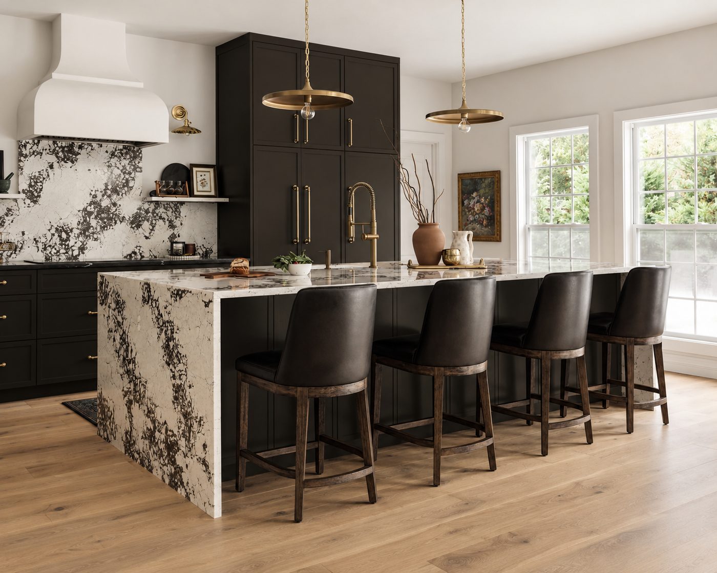 Kitchen with dark cabinets, a marble waterfall island, brass pendants and a white range hood