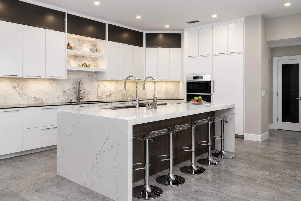 Modern white kitchen with flat panel doors and a quartz waterfall island with bar stools